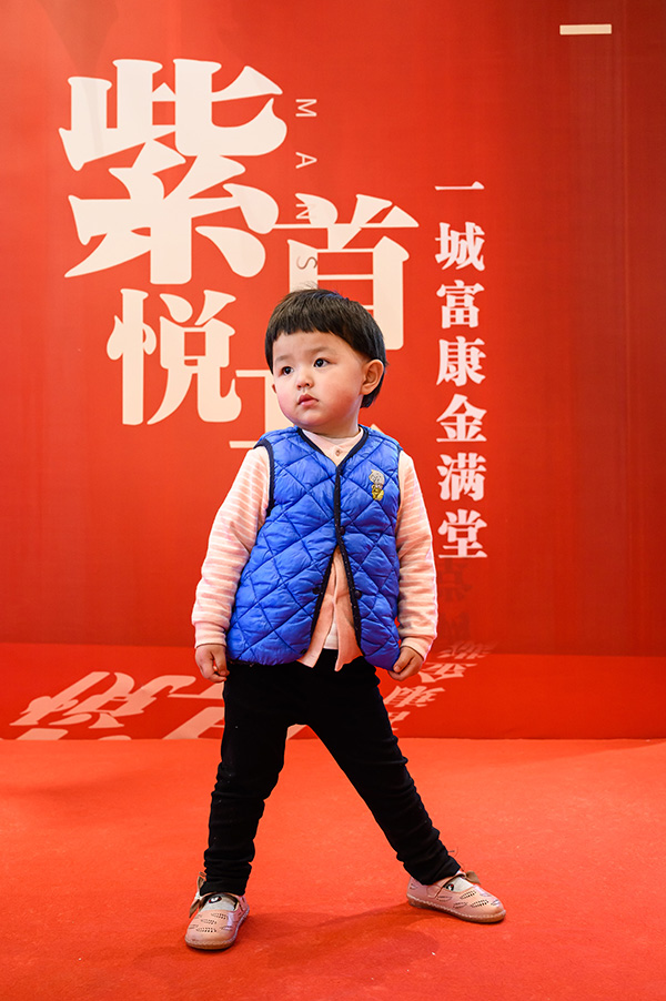 可爱的小朋友在会场里摆pose，家长在为他拍照。