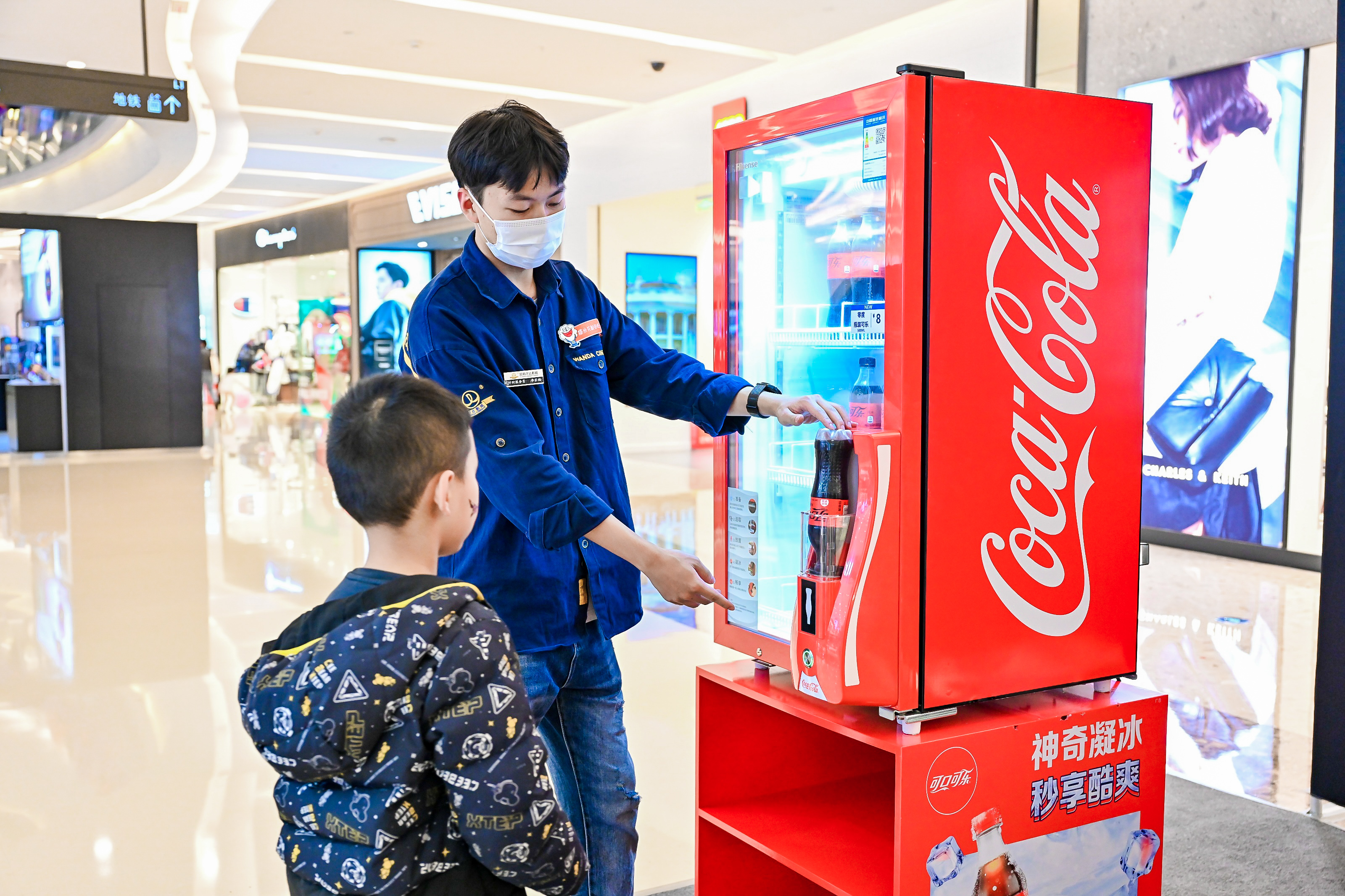 工作人员给小男孩展示制冰机有10秒钟内把可乐“冰镇”。